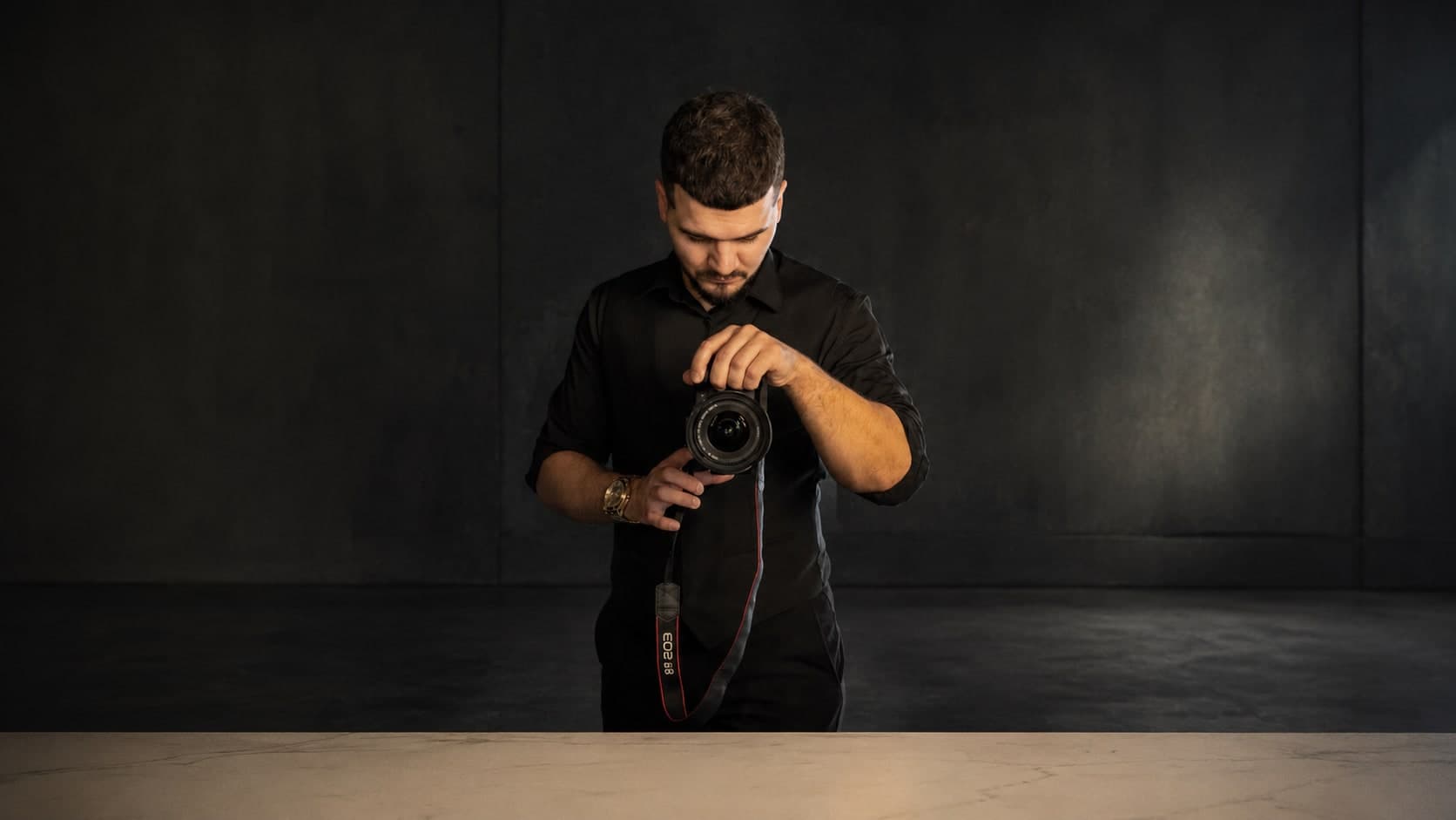 Serhio, Sydney fashion and street fashion photographer, holding his camera in a dark studio