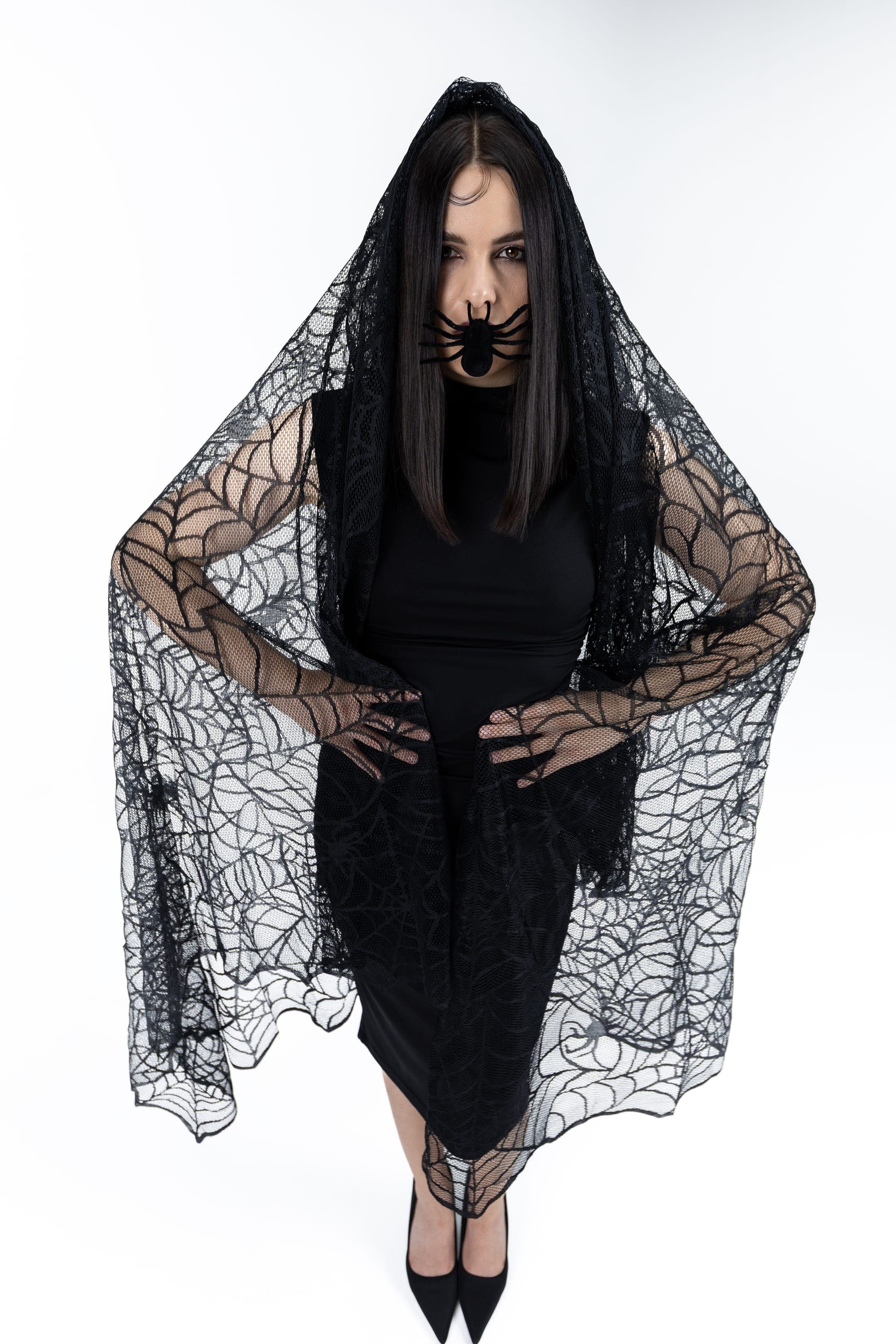 Model draped in a spiderweb-lace veil and black dress, Halloween-themed studio photography